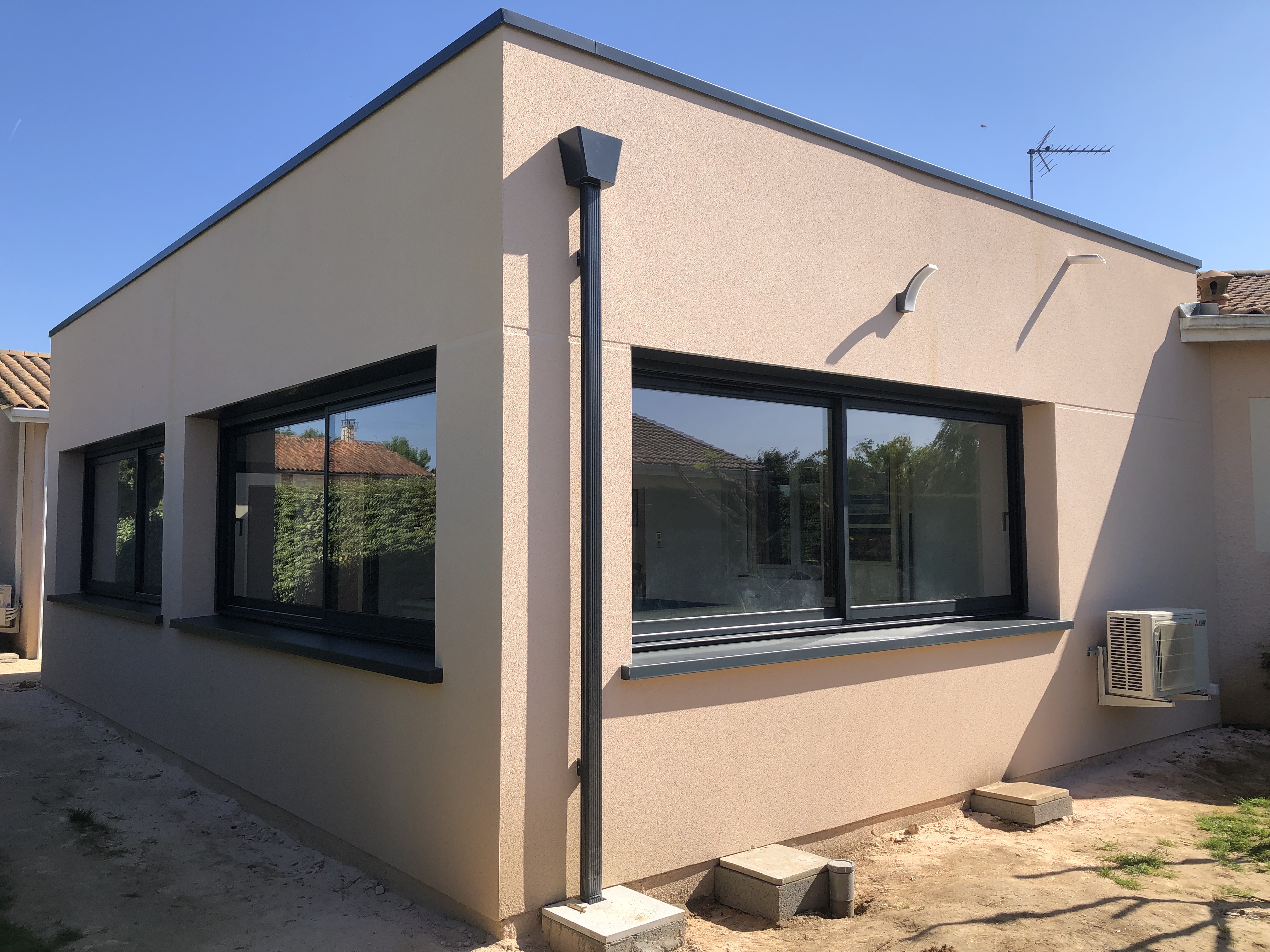 Façade d’immeuble rénovée en pierre claire avec menuiseries anthracite.