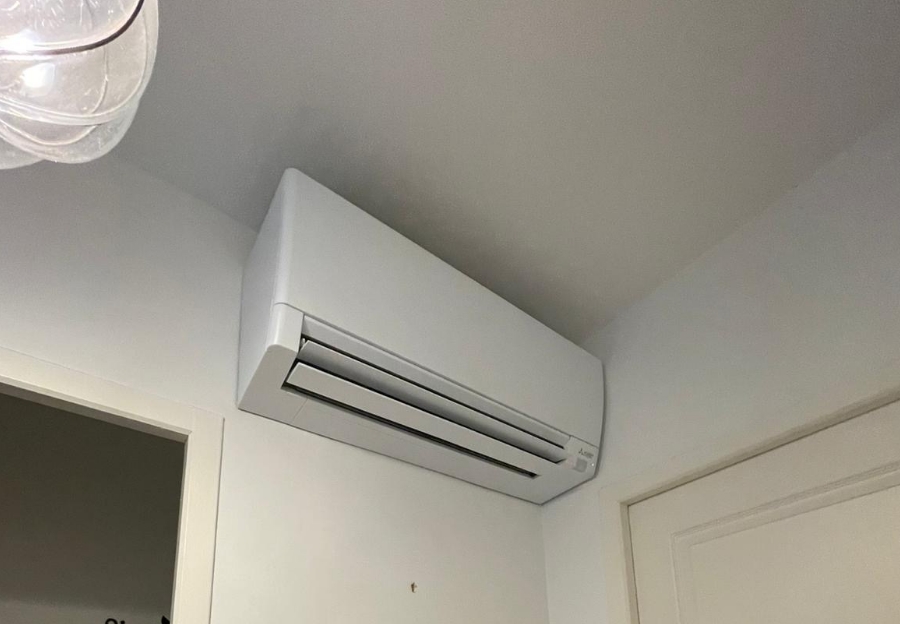 Unité intérieure de climatisation blanche installée au-dessus d’une porte.