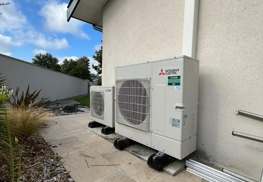 Deux unités extérieures Mitsubishi Electric installées le long d’une maison.
