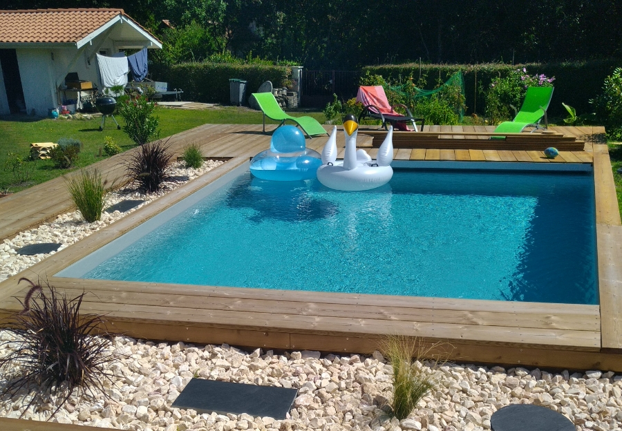 Piscine carrée entourée d’une terrasse en bois avec des bouées.
