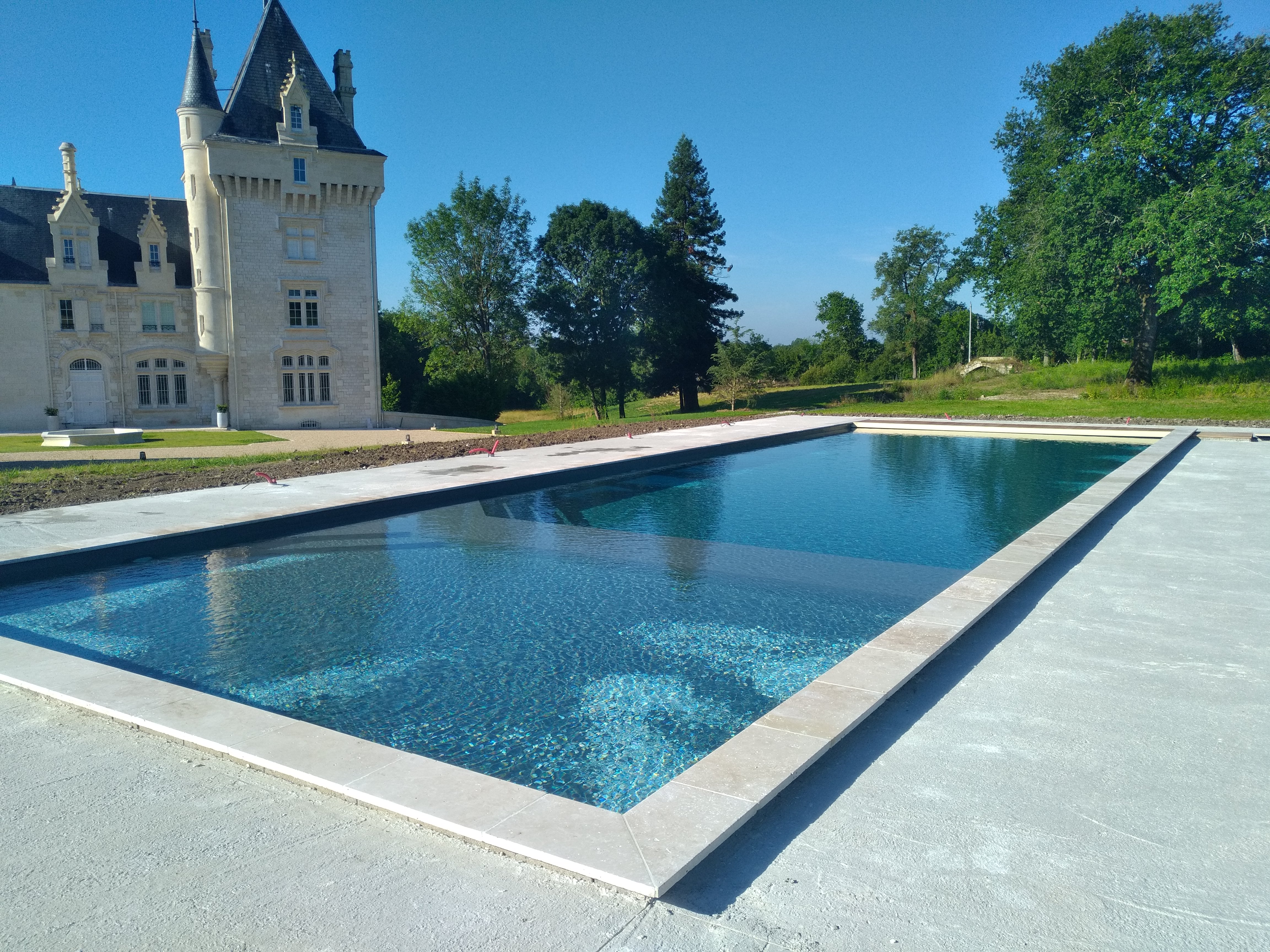 Grande piscine contemporaine aménagée devant un château.